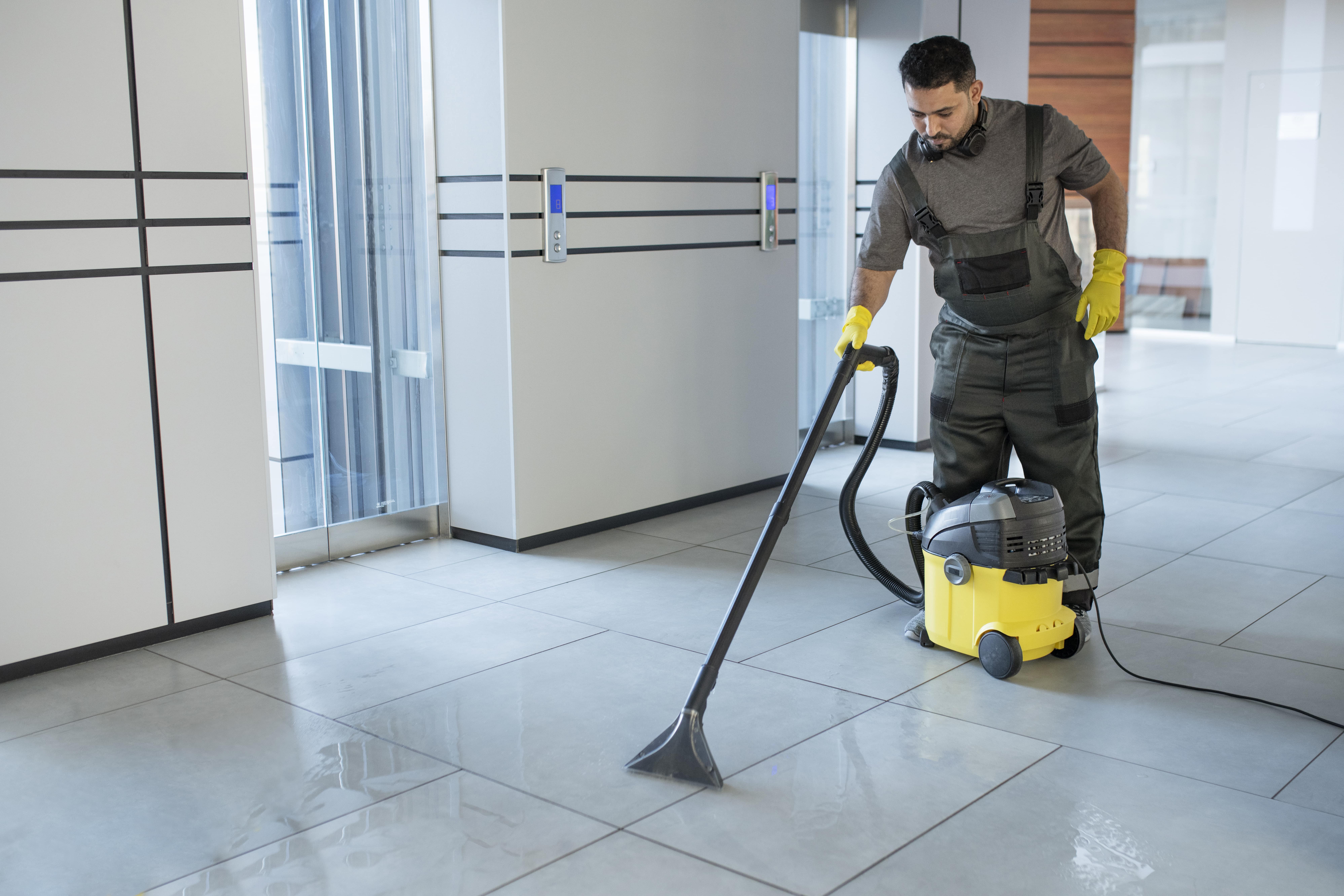 full-shot-man-vacuuming-office-floor-min